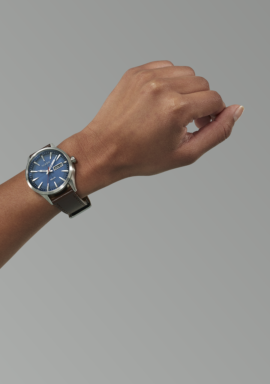 Wristwatch with a blue dial and silver-toned metal band worn on a person’s wrist.