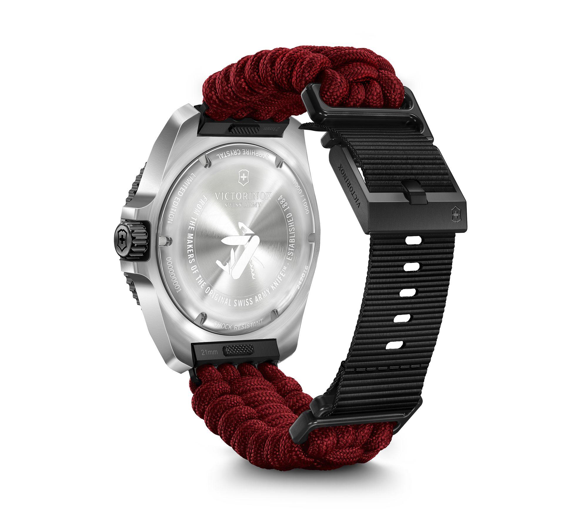 Wristwatch with a silver case, red braided band, and black rubber strap.