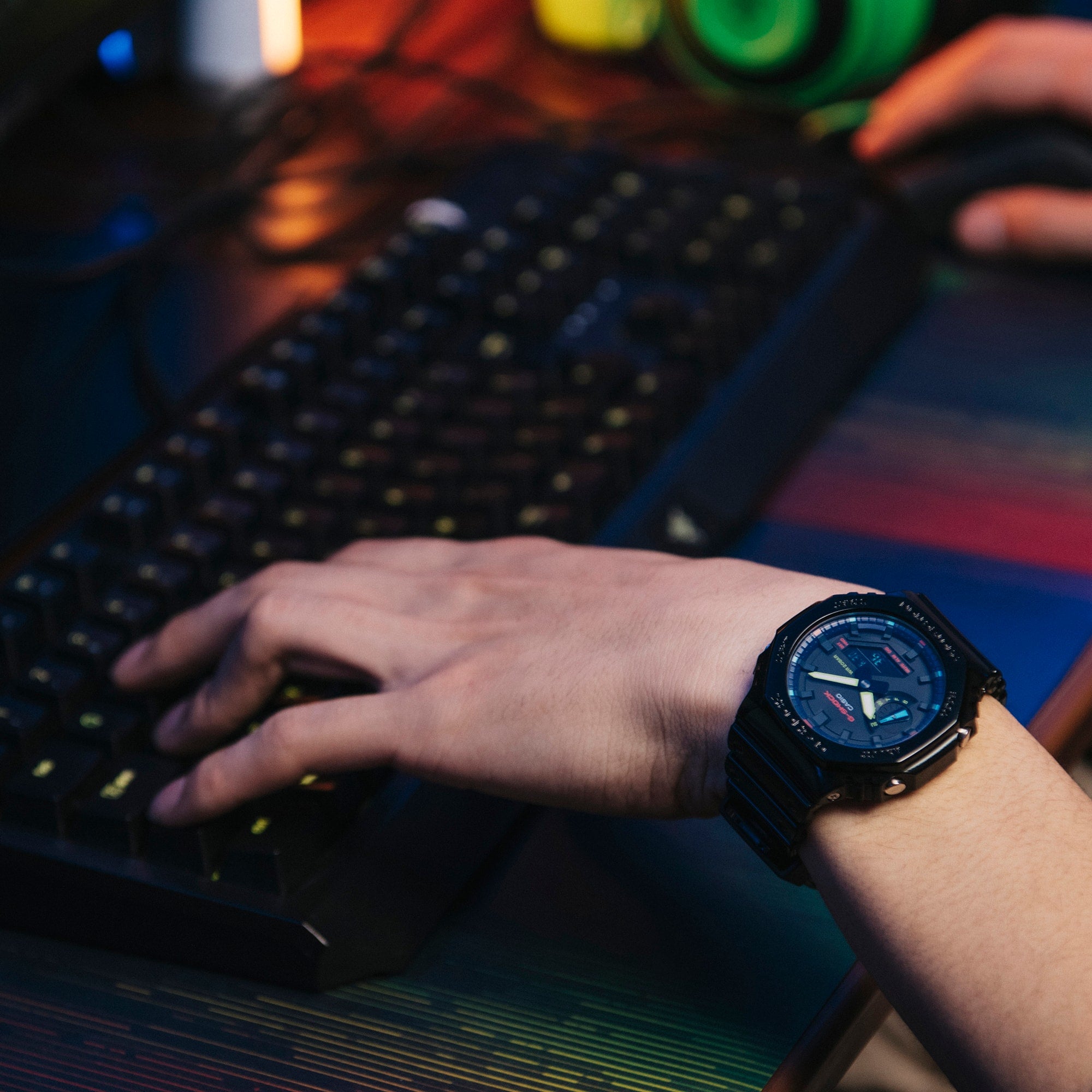 Stylish black wristwatch with a blue face worn on a person’s wrist as they type on a keyboard.