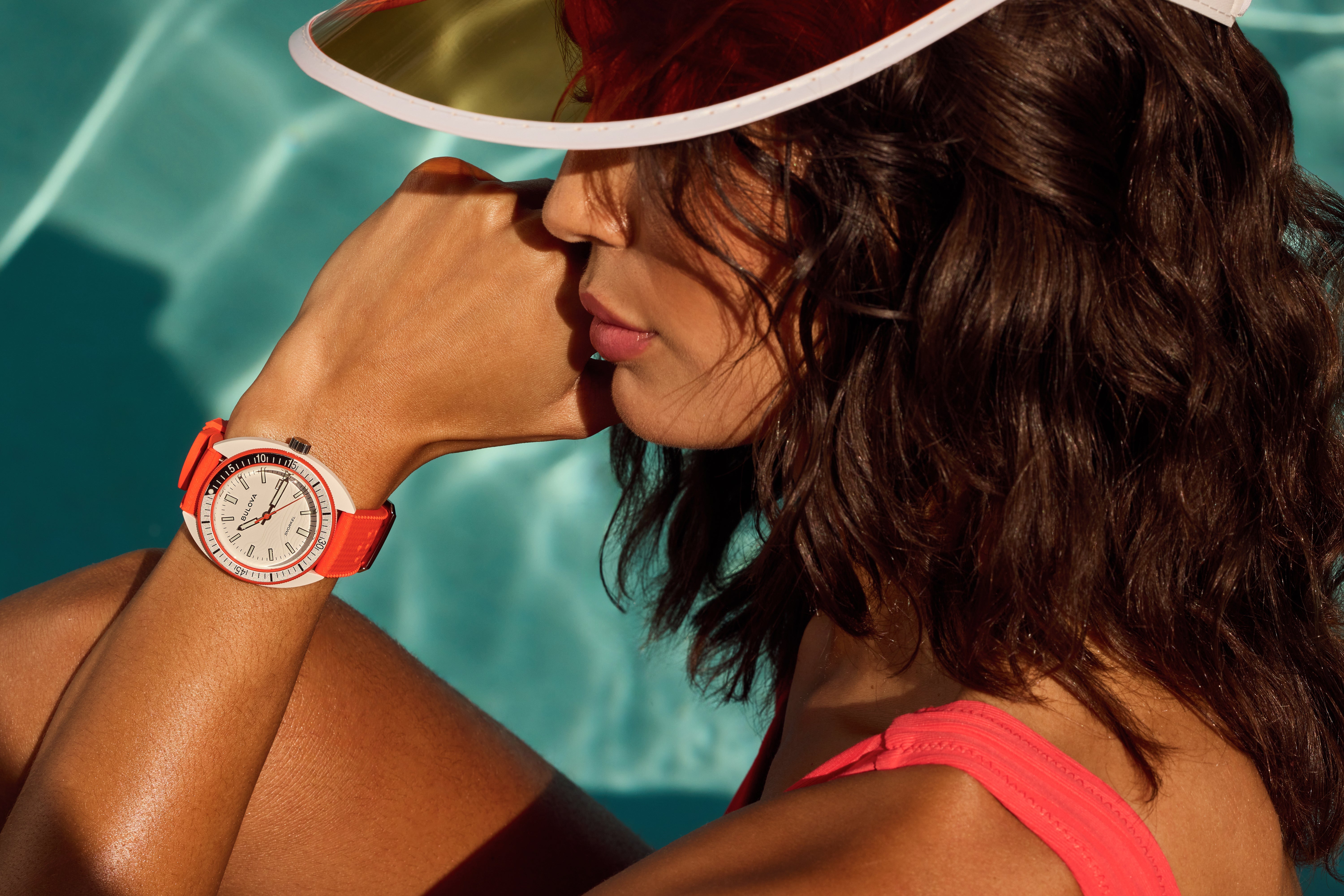 Woman wearing a Bulova Snorkel watch with an orange strap by the pool