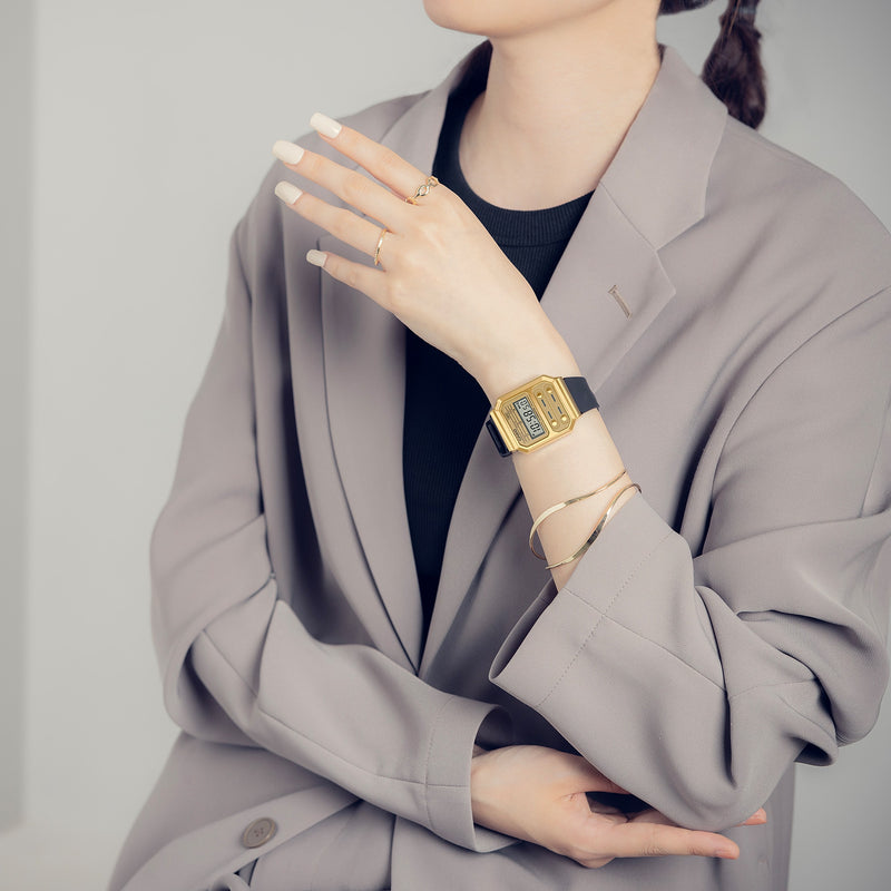 Gold wristwatch worn with a gray blazer.