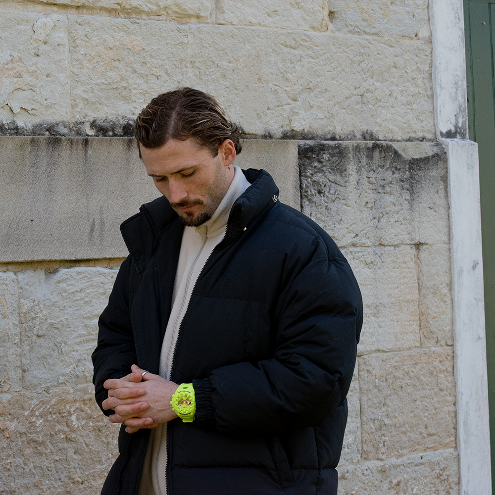Man wearing the bold G-Shock Ultimate Toughness Green Watch GAV01-9A by G-SHOCK in an outdoor urban setting.
