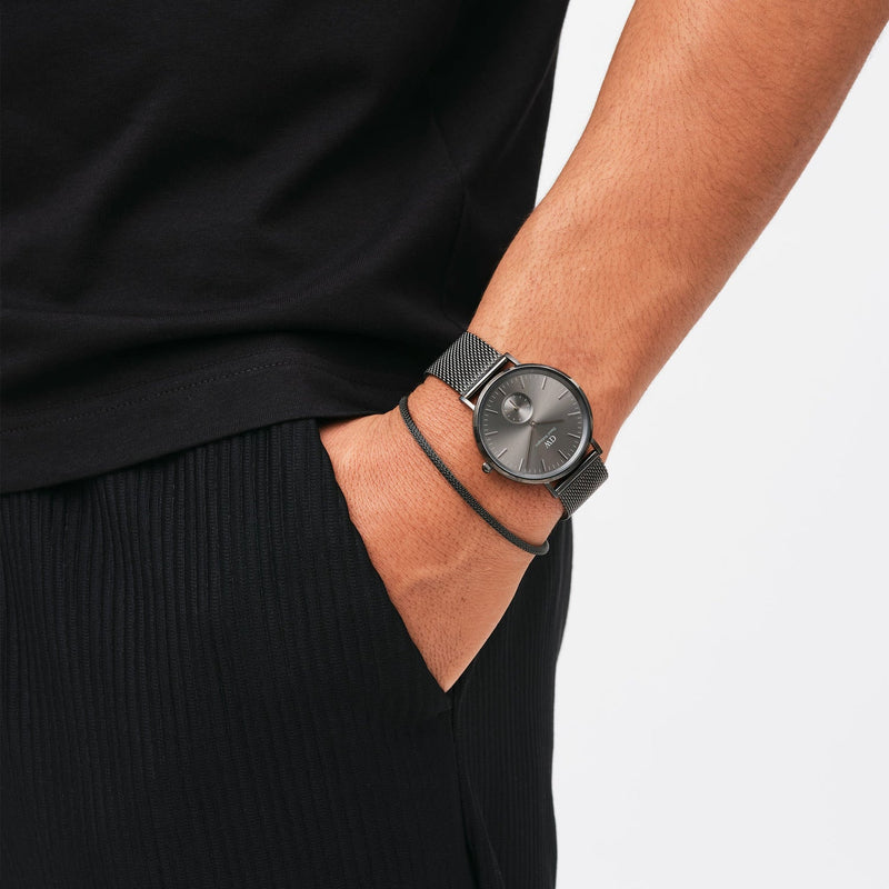 Sleek wristwatch with a dark face and mesh metal band.