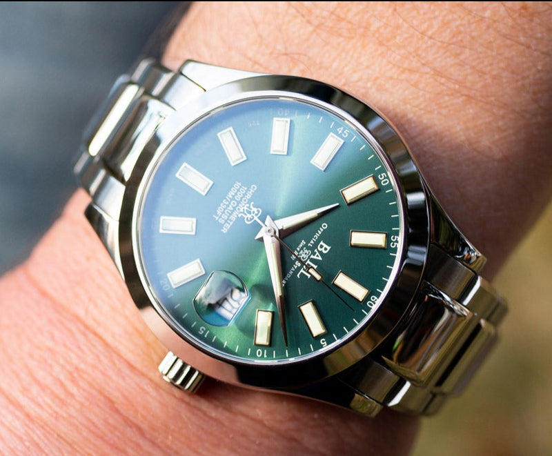 Luxury wristwatch with a green dial and silver metal bracelet.