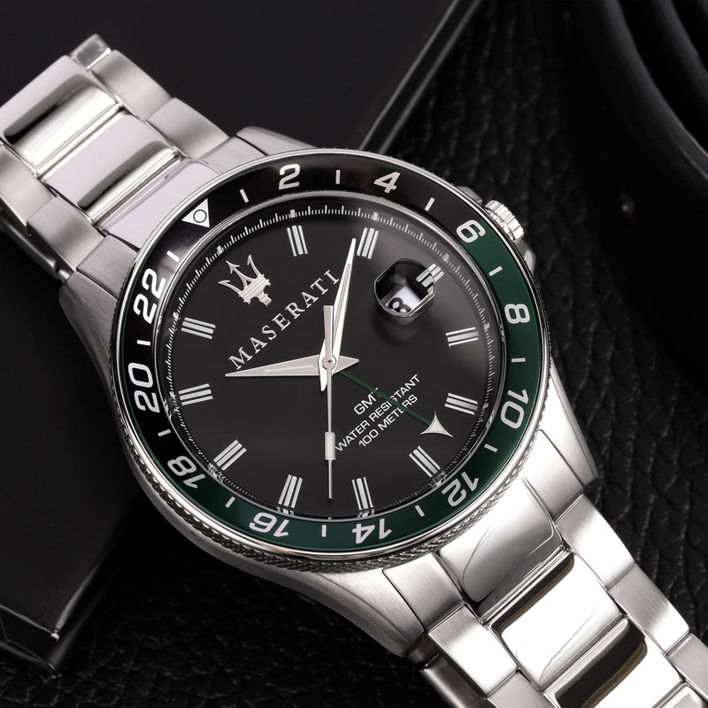 Luxury wristwatch with a black and green bezel and silver metal bracelet.