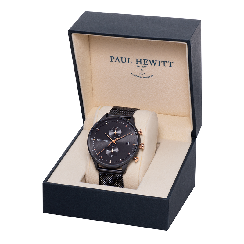 Black wristwatch with a mesh band displayed in an open presentation box.