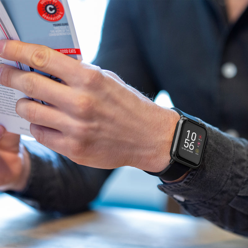 Smartwatch displaying time on a person’s wrist as they handle paperwork.