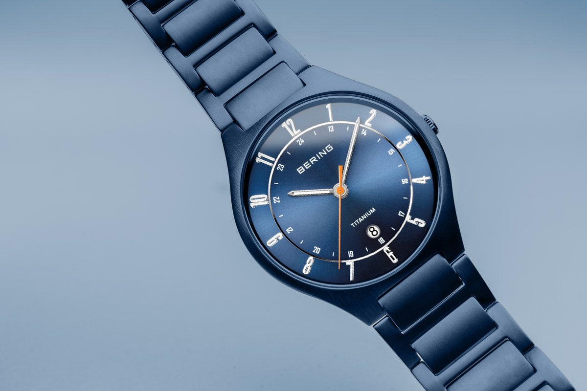 Navy blue wristwatch with a round face and metal bracelet.