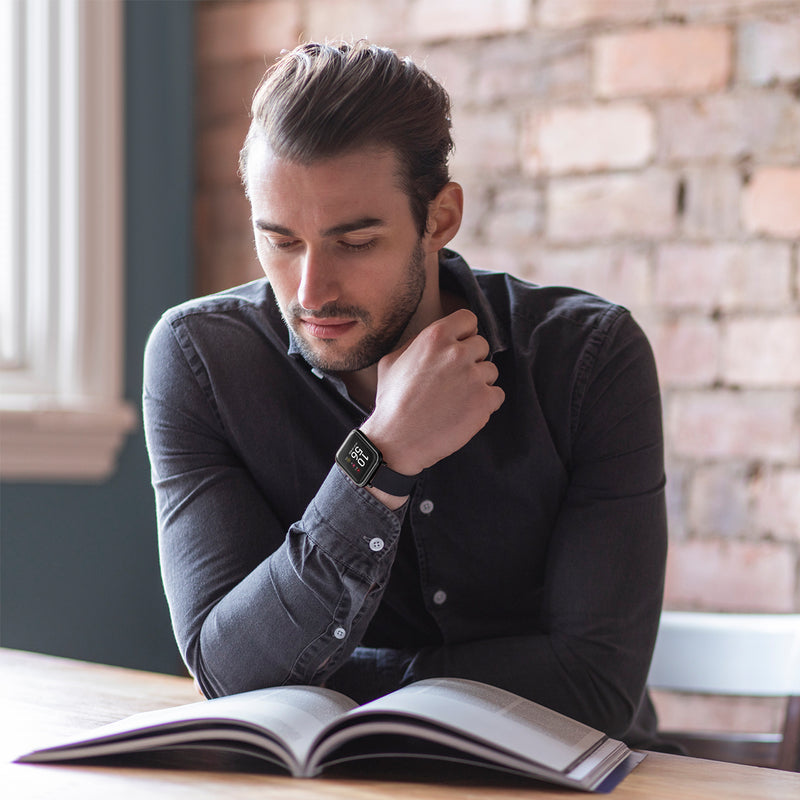 Man with beard reading a book while resting his chin on his hand.