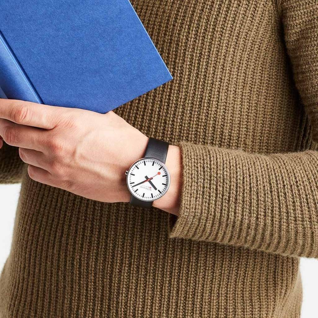 Wristwatch with a white face and simple design on a person’s arm.