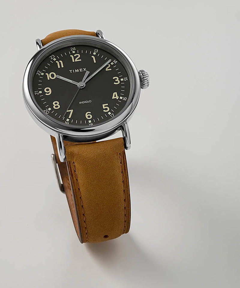 Vintage-style wristwatch with a black dial and tan leather strap.