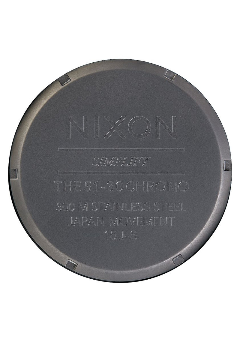 Circular metal watch case back with engraved text including the brand name ’Nixon’.