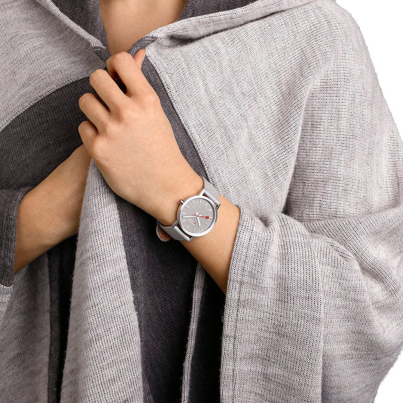 Wristwatch with a gray band and minimalist round face worn on a person’s wrist.