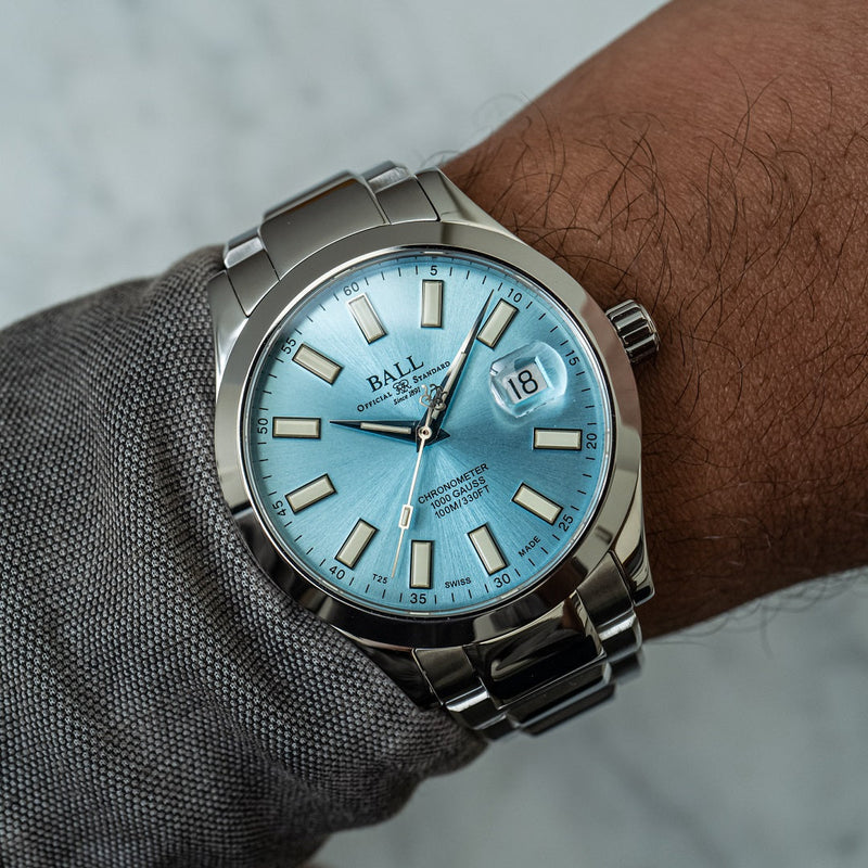 Ball wristwatch with a light blue dial and silver metal bracelet.