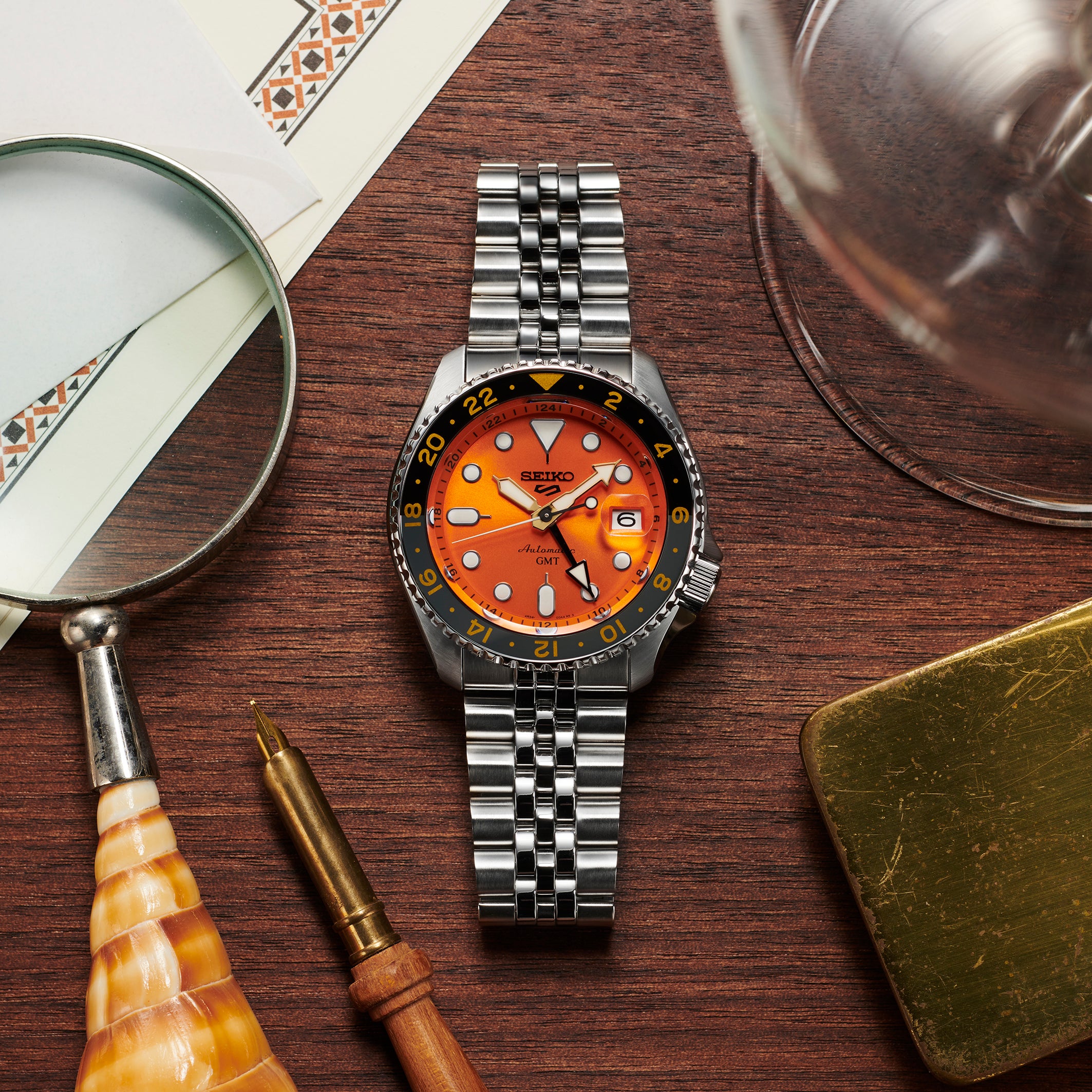 Stainless steel wristwatch with an orange dial and black bezel.