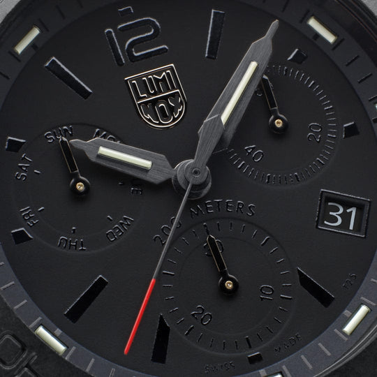 Close-up view of a black Luminox wristwatch face with multiple dials and a red second hand.