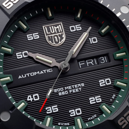 Close-up view of a Luminox watch face with green hour markers and a day-date display.