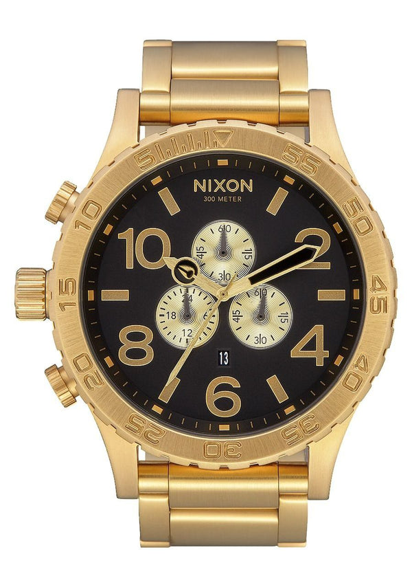 Gold-toned Nixon chronograph wristwatch with a black dial and multiple subdials.