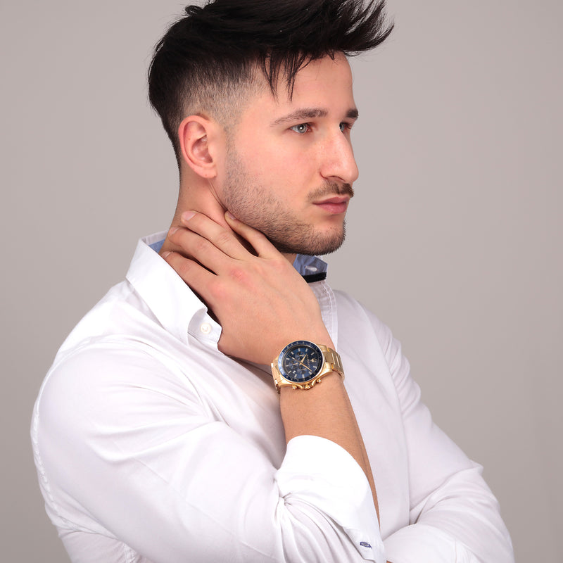 Man with styled dark hair wearing a white shirt and gold watch.